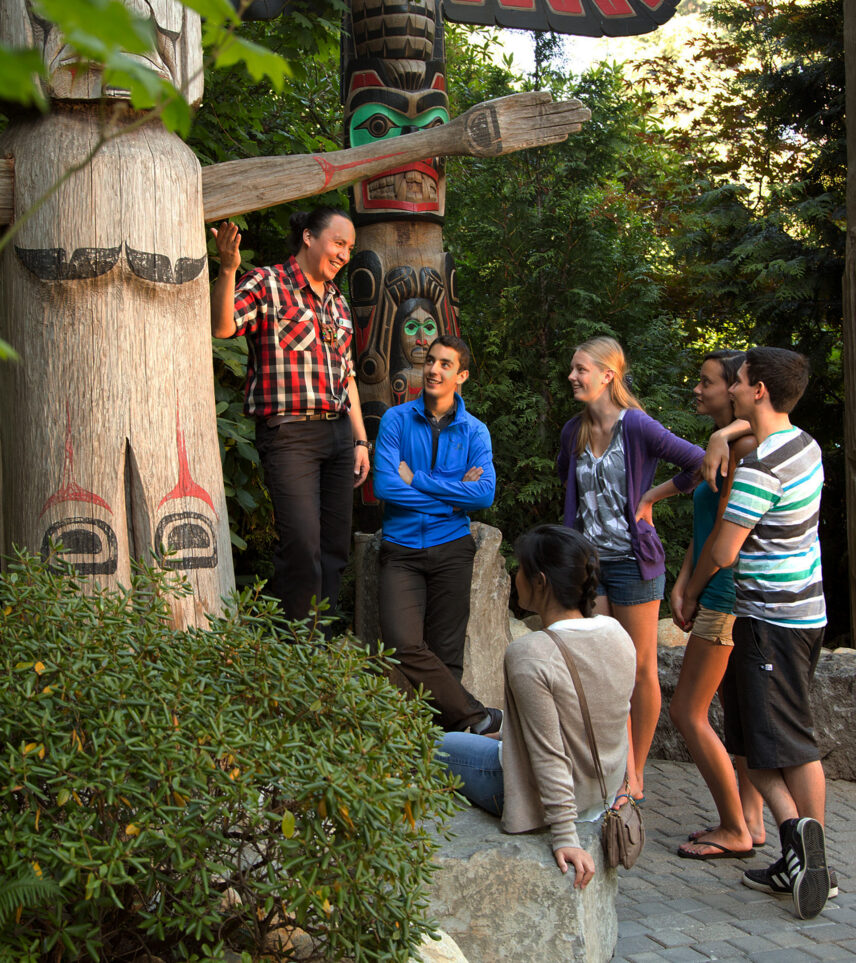 Tour guide with group of guests at Kia'palano totem poles at Capilano Suspension Bridge Park