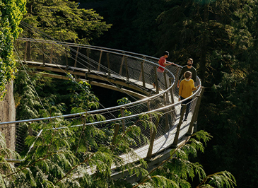Guests enjoy a scenic walk along the Cliffwalk attraction on a sunny summer day at Capilano Suspension Bridge Park, immersed in breathtaking views and thrilling experiences