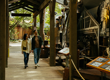 A couple strolls through the Story Centre, while looking at the historical displays, immersed in the fascinating narratives of Capilano Suspension Bridge Park's past.